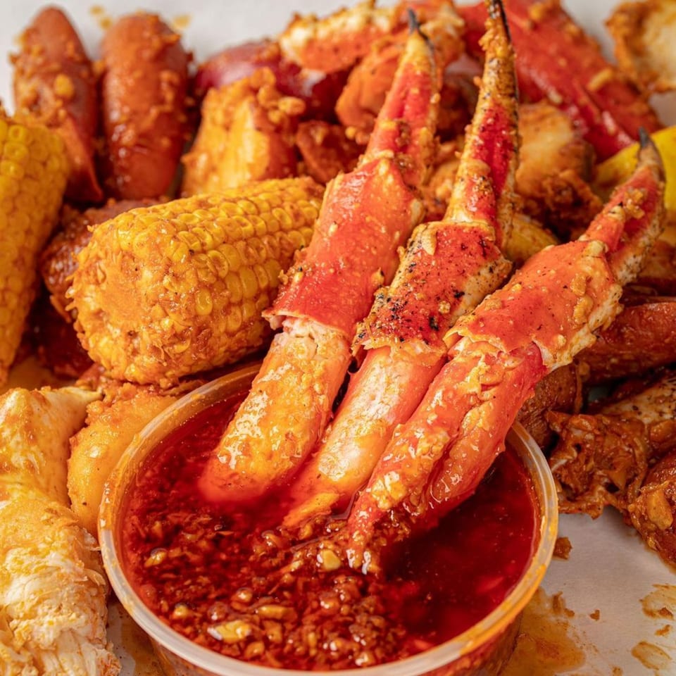 Boil Daddy's seafood boil with crab legs, corn, and potatoes, served with a spicy dipping sauce.